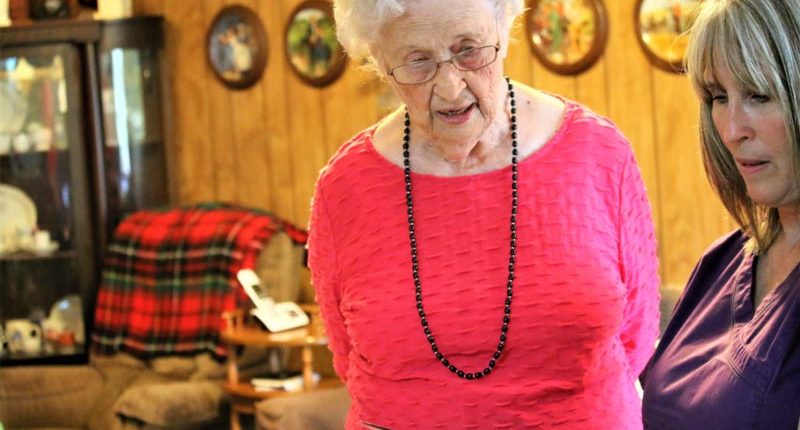 Nederland TX home care caregiver looking at photo album with senior client in hot pink