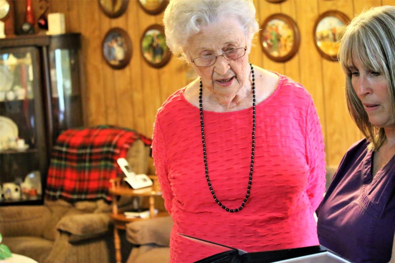 Nederland TX home care caregiver looking at photo album with senior client in hot pink