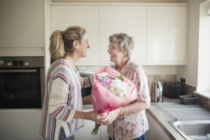 A caregiver providing Vidor home care services, brings flowers to an elderly female client.