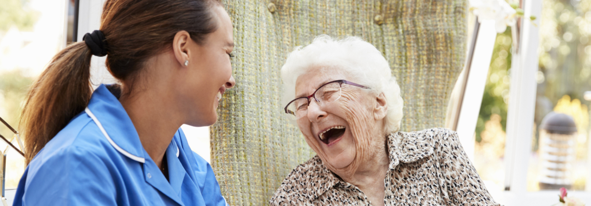 A caregiver providing senior companionship care in the Beaumont area and senior woman share a laugh together.